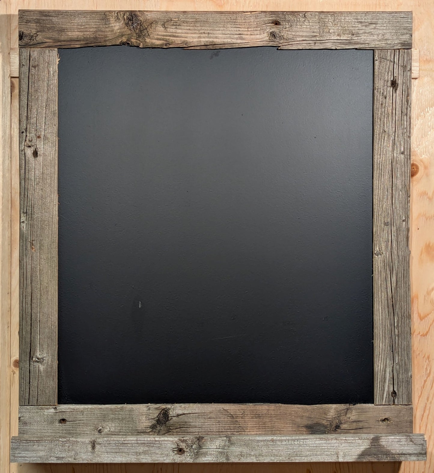 A Barn Board scoreboard, made of reclaimed wood, featuring a ledge for chalk and a brush.
