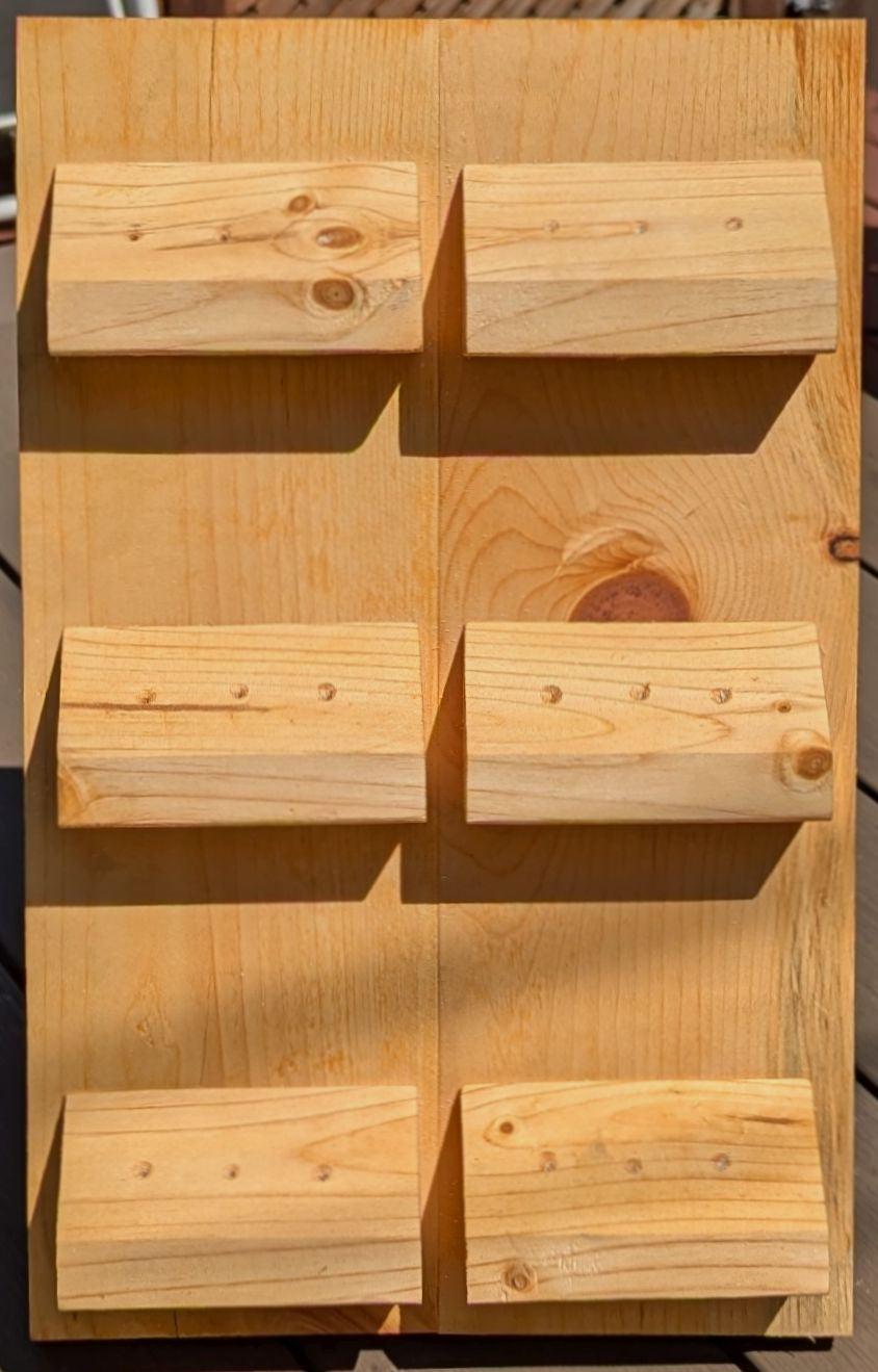 A solid pine board with angled wedges to display 6 sets of darts (18 darts). Finished with red cedar oil finish.