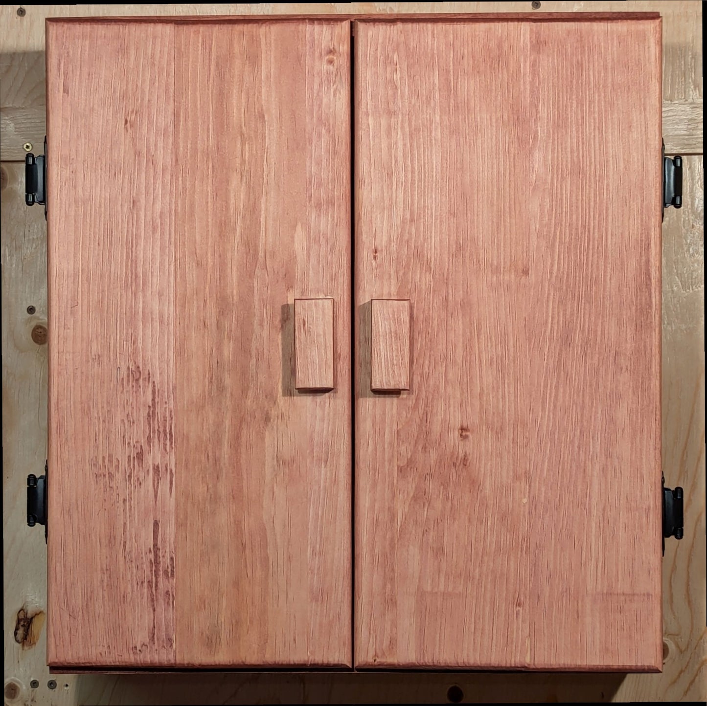 A solid pine dartboard cabinet finished in a Sedona Red color.