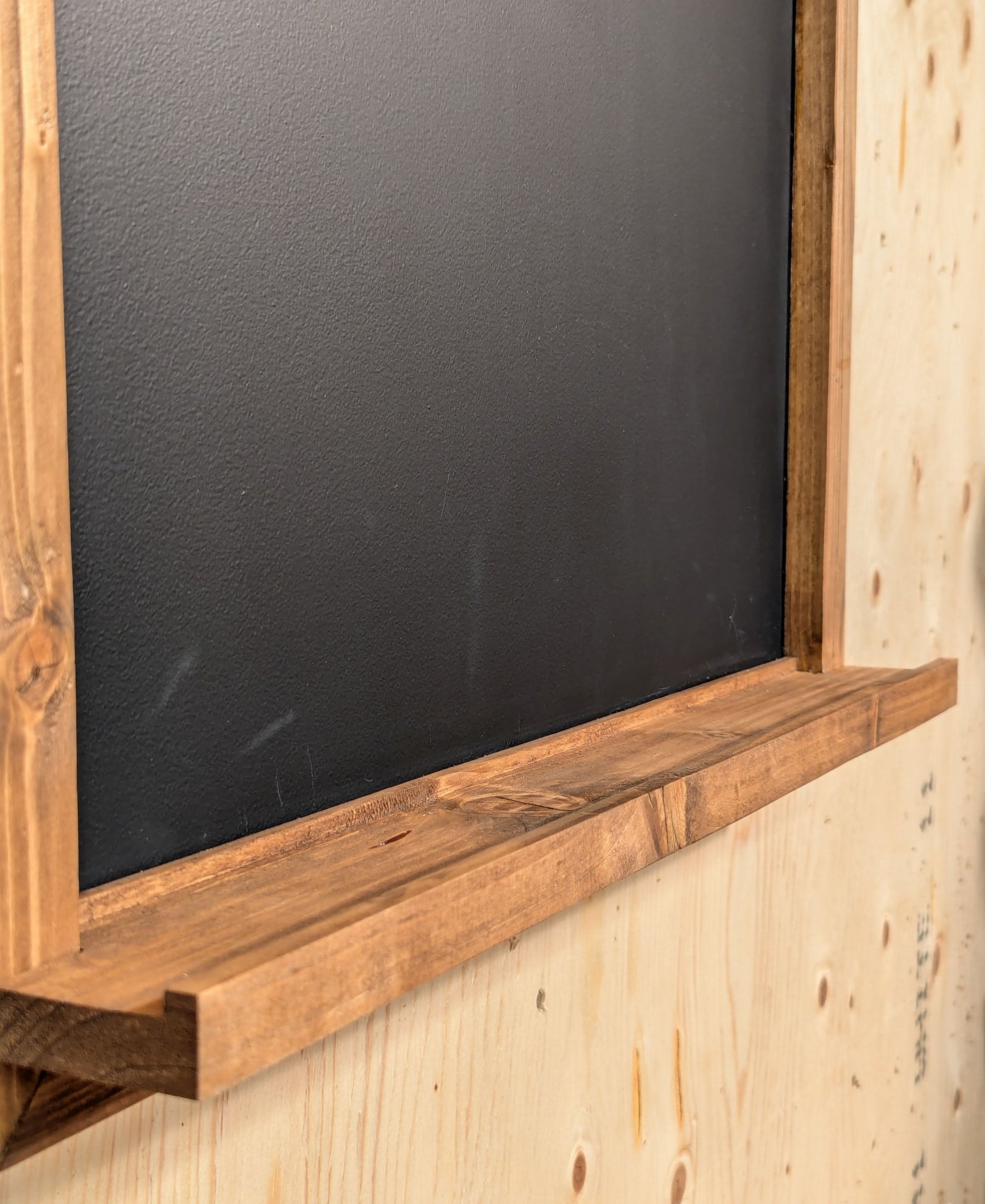 The ledge of a darts scoreboard illustrating the groove for chalk and eraser.